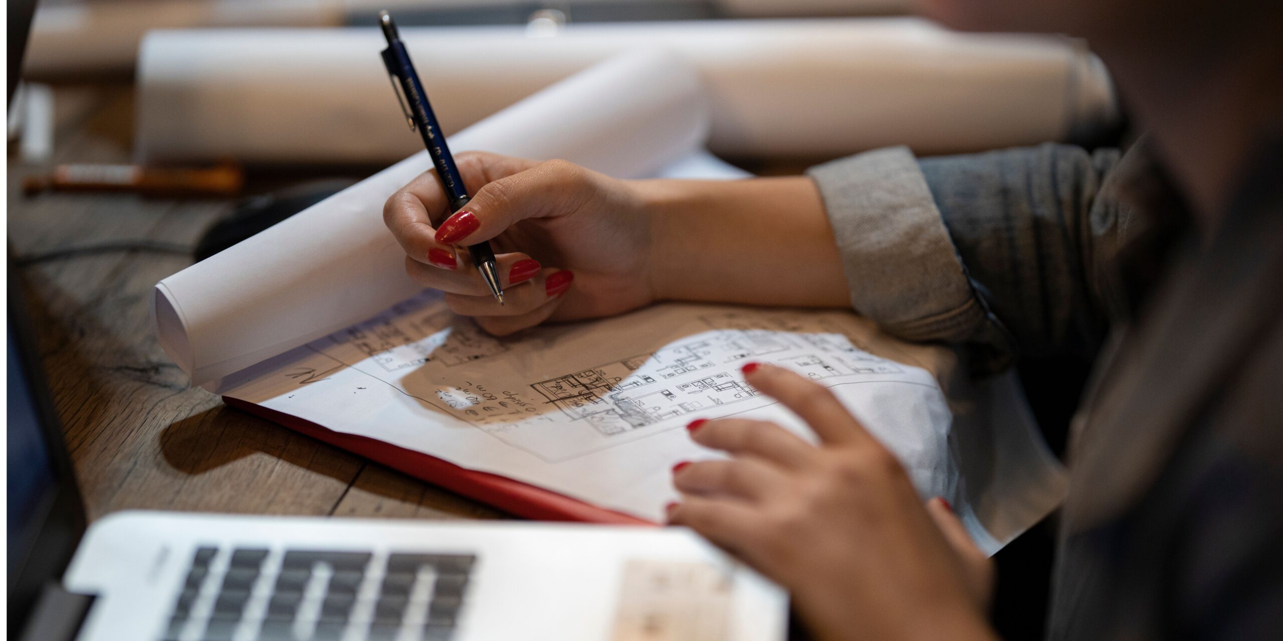 girl writing on paper next to a computer